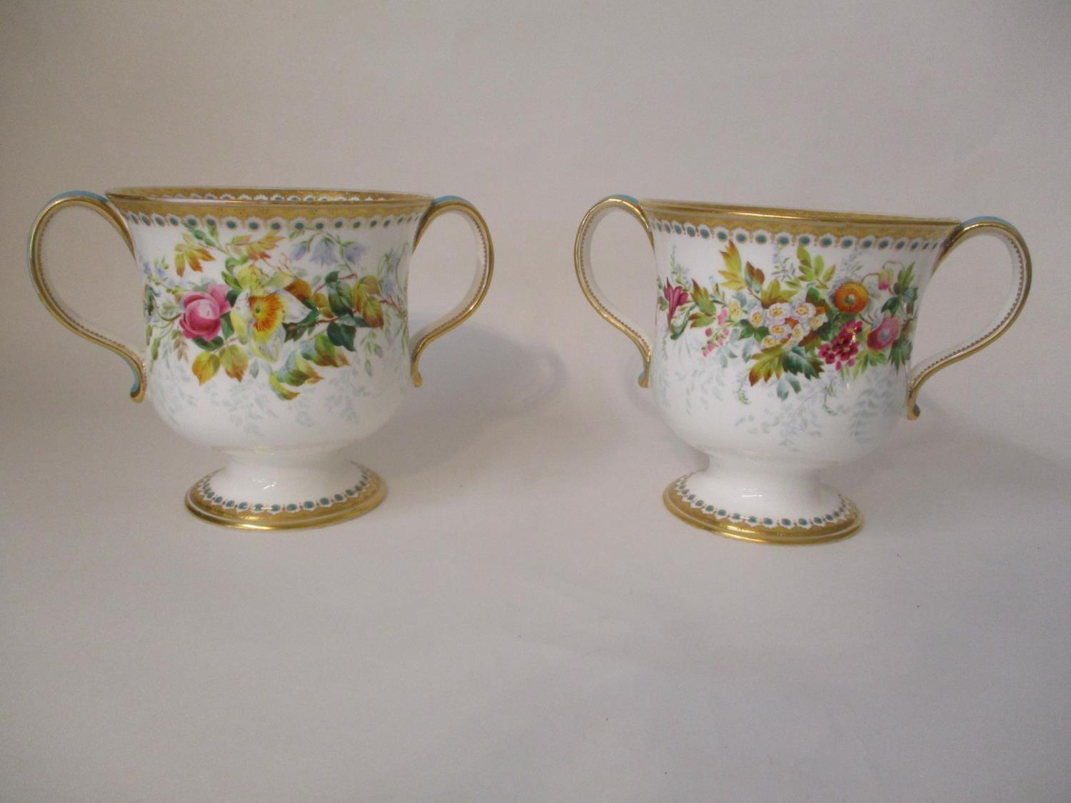 A pair of early 20th century English porcelain twin handled cups, on a splayed foot decorated with