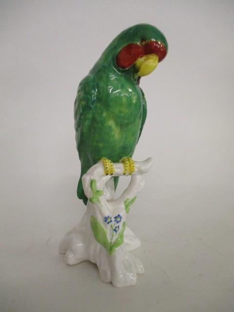 A Copeland Spode china model of a green parrot with red and pink markings and a yellow beak, perched