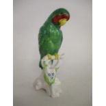 A Copeland Spode china model of a green parrot with red and pink markings and a yellow beak, perched