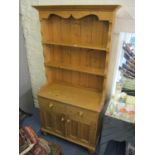 A small modern pine dresser having a plate rack above two short drawers and cupboards doors, 76" h x