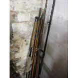 Various cane and graphite fishing rods and a cast metal, leather and wooden shooting stick