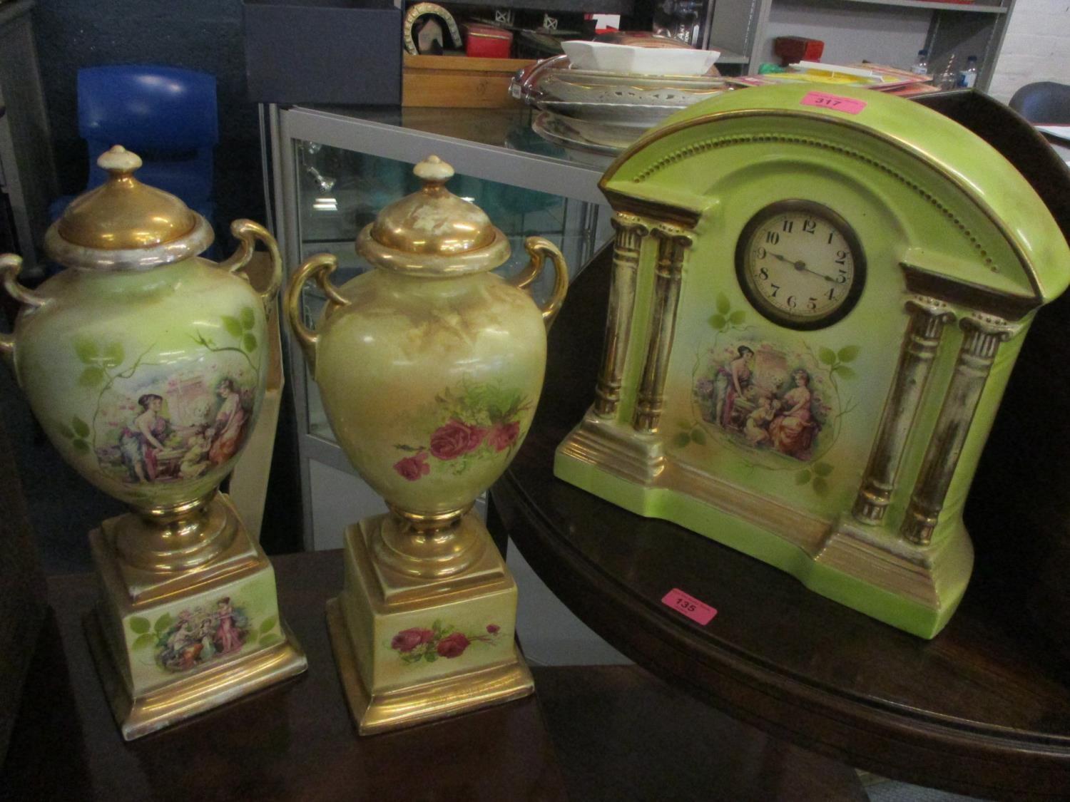 A late 19th/early 20th century porcelain painted mantel clock and a pair of matching vases A/F