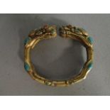 A modern gilt metal dragon headed bangle, inset with tear drop shaped turquoise and coral eye, the