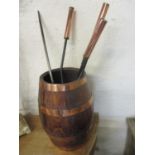 A 1930s oak and copper coopered barrel, along with copper and iron fire irons