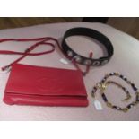 A red leather fashion should bag, a black leather belt with circular fastener, together with a