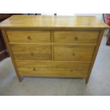 A modern oak chest of four short drawers and one long drawer on square legs