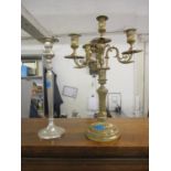 An ornate brass three-branch candelabra and a silver plated candlestick