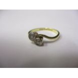 An 18ct gold and platinum diamond, two stone cross over ring