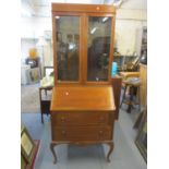 A 1920s walnut bureau bookcase having twin glazed doors above a fall flap and two drawers, 77" h x