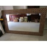 G Kent - a contemporary wooden framed wall mirror, the wood surround with a burnt and cut