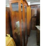 A modern mahogany finished breakfront display cabinet with a central door enclosing glass shelves