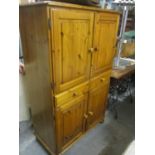 A modern pine cabinet having four cupboard doors, two drawers and bun shaped handles