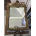 A late 19th century gilt gesso mirror with scrolled leaf and flower ornament, 24" x 15"