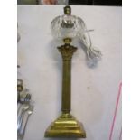 A brass table lamp having a Corinthian column and a glass reservoir