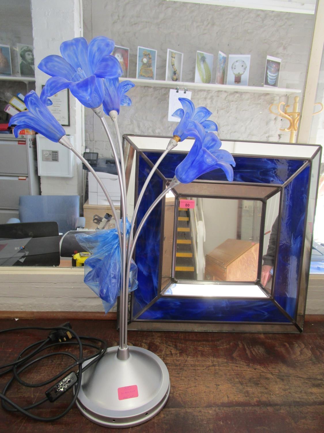 A contemporary silver coloured table lamp with four swirled blue glass flower head shaped shades,