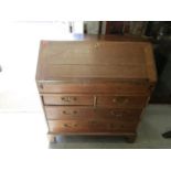 A George III oak bureau, fall flap revealing a fitted pigeonhole and drawer interior, over two short