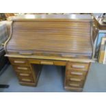 An early 20th century roll top, tambour fronted desk having one long drawer flanked by eight short