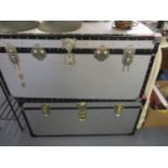 Two large silver coloured metallic travelling trunks
