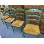 A group of four green painted chairs with caned seats