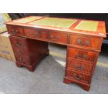 A reproduction yew twin pedestal desk, the central drawer flanked by five short cupboards on a