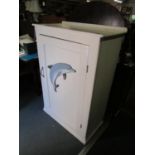 A white painted pine cabinet with single fielded door with applied dolphin plaque 50 1/2" x 34" x 17