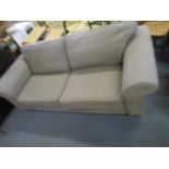 A large grey upholstered two seater sofa on light wood block feet