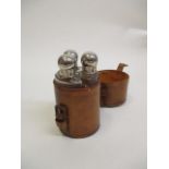 A leather cased set of three glass bottles with stoppers and caps, 5" h