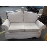 A two person sofa upholstered in an oatmeal coloured fabric