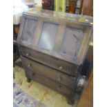 A mid 20th century oak bureau having a fall flap above three drawers