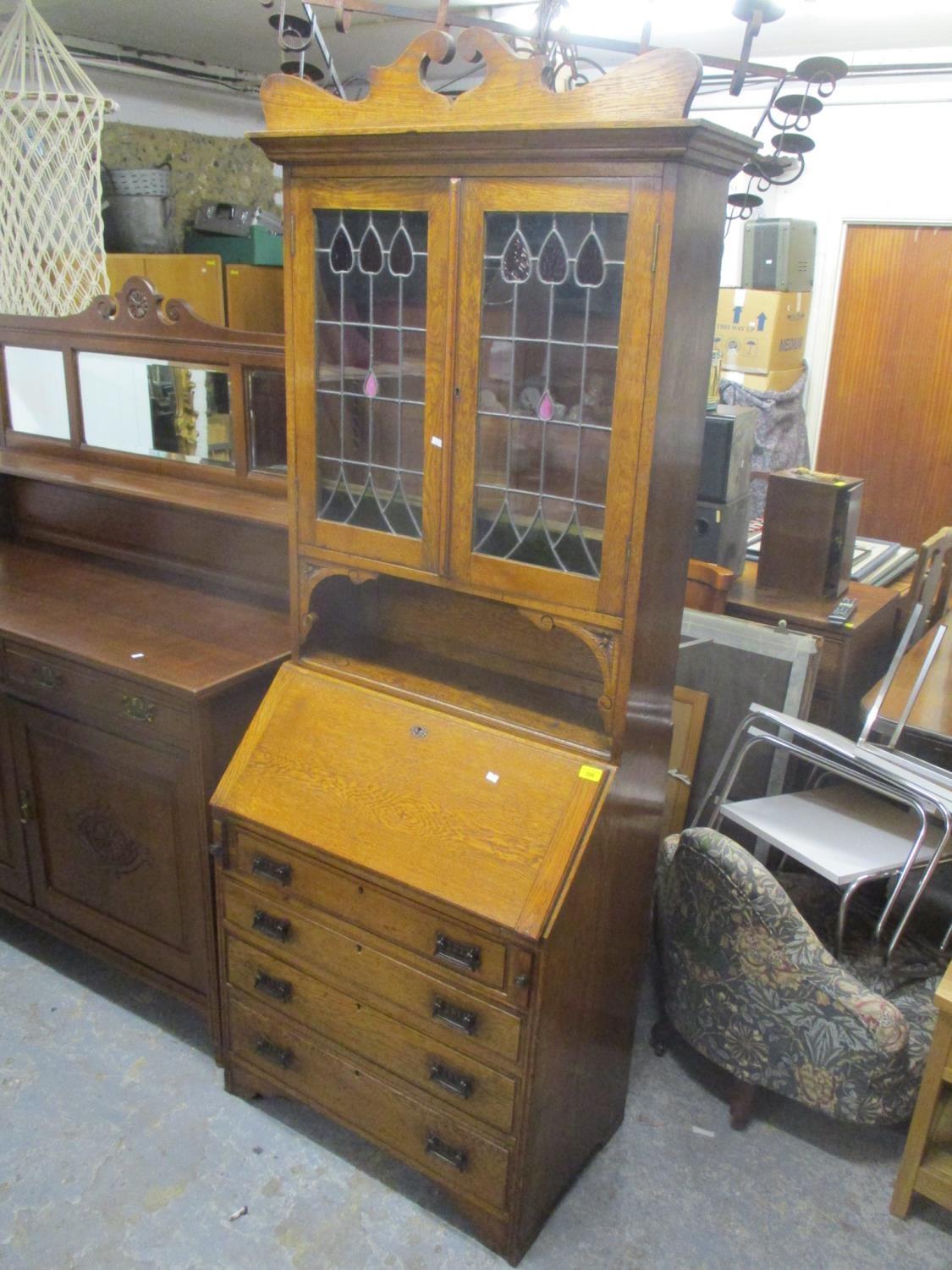 An Arts and Crafts oak bureau bookcase having coloured early 20th century glass panels above fall