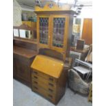 An Arts and Crafts oak bureau bookcase having coloured early 20th century glass panels above fall