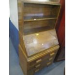 An early 20th century oak bureau having two open shelves above a fall flap and three drawers