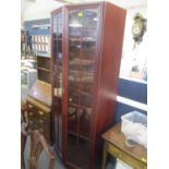 A modern mahogany finished bookcase having twin glazed doors standing on a plinth base, 79 1/2" h