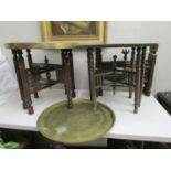 Three early 20th century Middle Eastern carved folding wooden tables, each with a brass tray