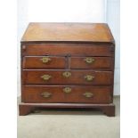 An early 18th century walnut bureau with a feather and crossbanded fall flap enclosing a well,