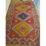 A Middle Eastern red ground rug having three medallions, multiguard borders and geometric designs,