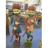 A pair of modern Indian polychrome painted, carved wooden figures, each of a man holding a staff, on