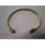 A 9ct yellow gold bangle, each end terminating in ball-shaped ends, Birmingham 1998, maker JAM,