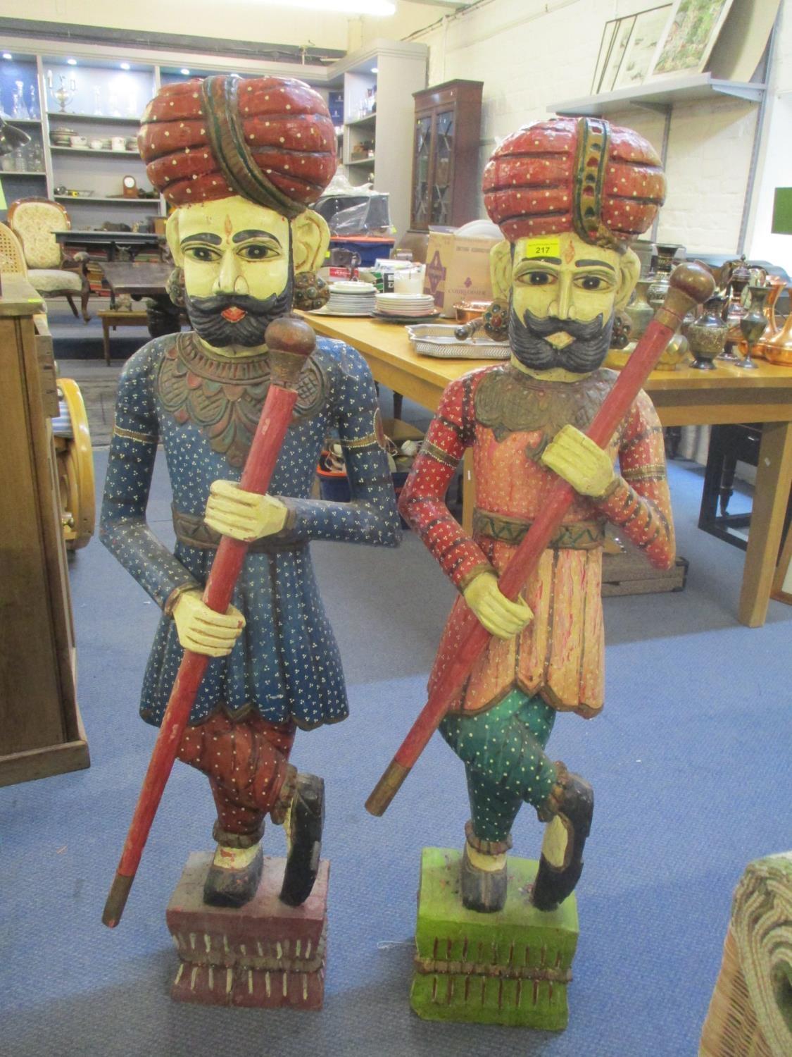 A pair of modern Indian polychrome painted, carved wooden figures, each of a man holding a staff, on