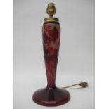 A cameo brown/red opaque glass lamp base decorated with vines, leaves and flowers, on a splayed foot