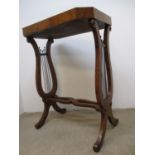 An early 20th century burr elm table with a deep moulded top, over lyre shaped ends with brass rods,