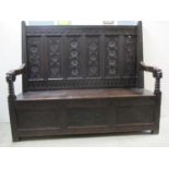 An 18th century and later oak settle with a rosette carved, panelled back, mask arms, bobbin