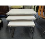 A nesting set of three retro occasional tables, each with a white Formic top on chrome tubular