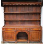 A George III oak dresser with an adapted twin shelf back, above three inline drawers, an open