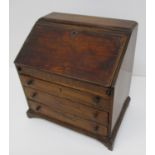 A 19th century walnut apprentice piece bureau with a hinged, fall flap enclosing a well, pigeonholes