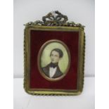 A 20th century brass frame with ribbon, bow and rope twist ornament containing a portrait