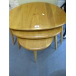 An Ercol light elm nest of three pebble tables