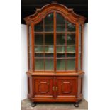 A 19th century European pine display cabinet with a moulded cornice over a pair of glazed,