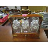 A Victorian oak and brass bound Tantalus with three cut glass whisky decanters and stoppers, with