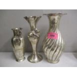 Three white metal vases, two decorated with roses